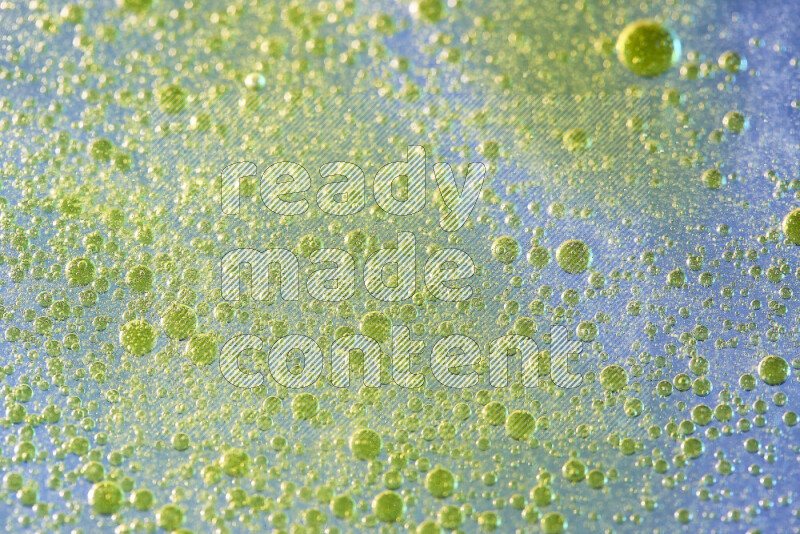 Close-ups of abstract yellow watercolor drops on oil Surface on blue background