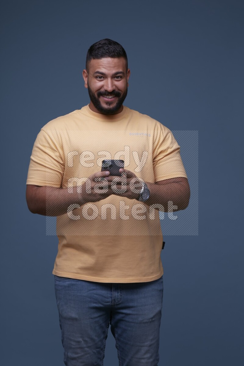 A man Texting on his phone in Blue Background wearing Orange T-shirt