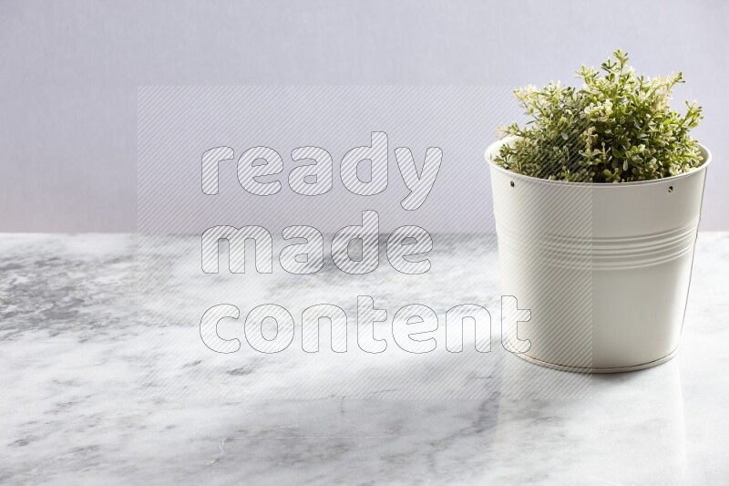 Artificial plant in white pot on grey marble background