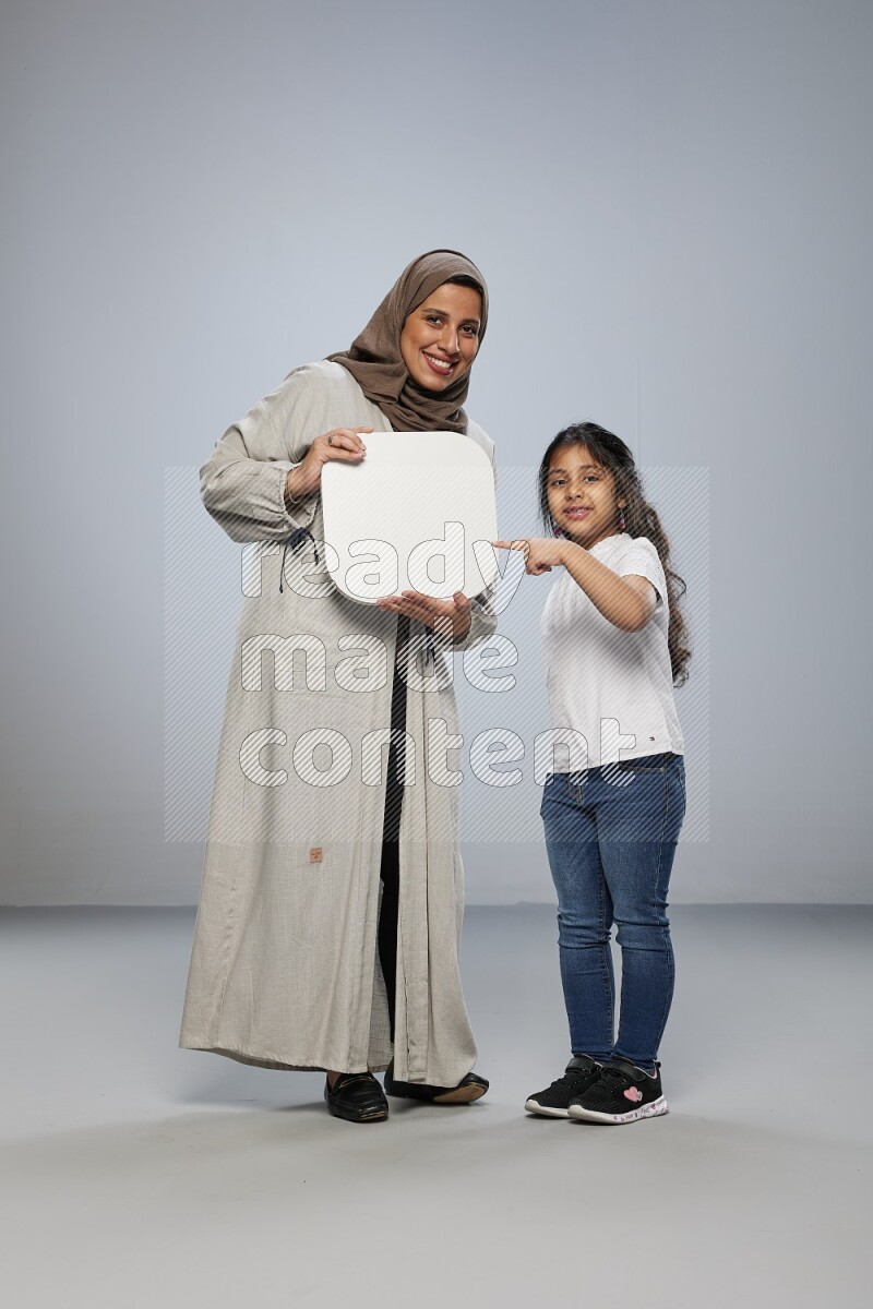 Mom and daughter standing holding social media sign on gray background