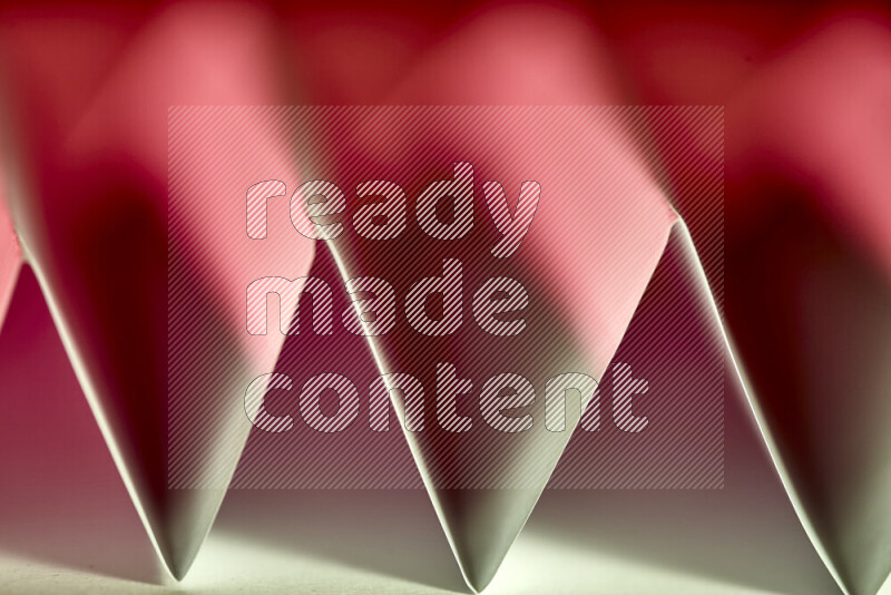 A close-up abstract image showing sharp geometric paper folds in green and red gradients