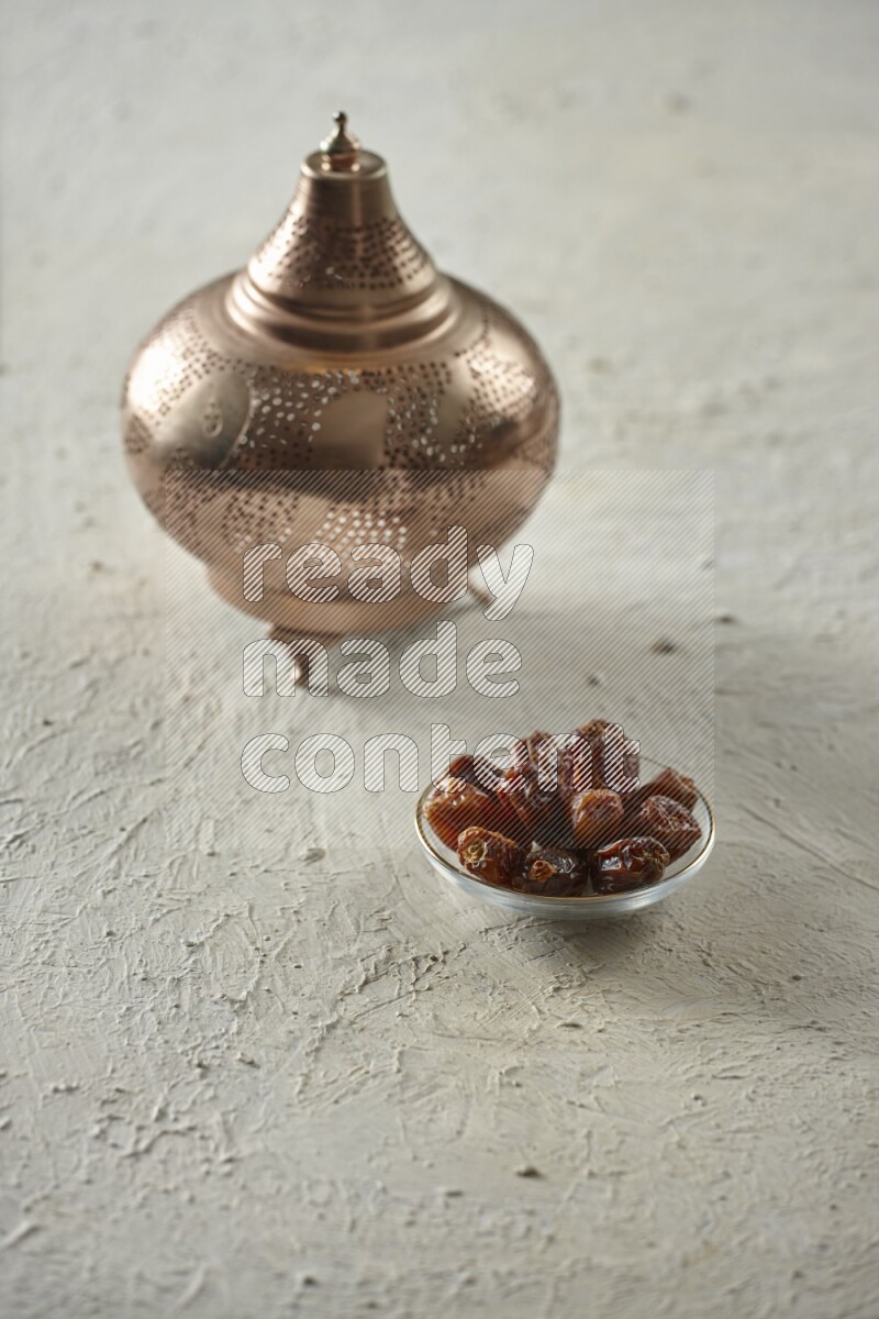 A golden lantern with different drinks, dates, nuts, prayer beads and quran on textured white background