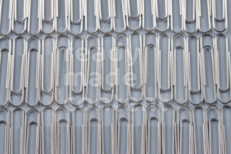Silver paper clips isolated on a grey background