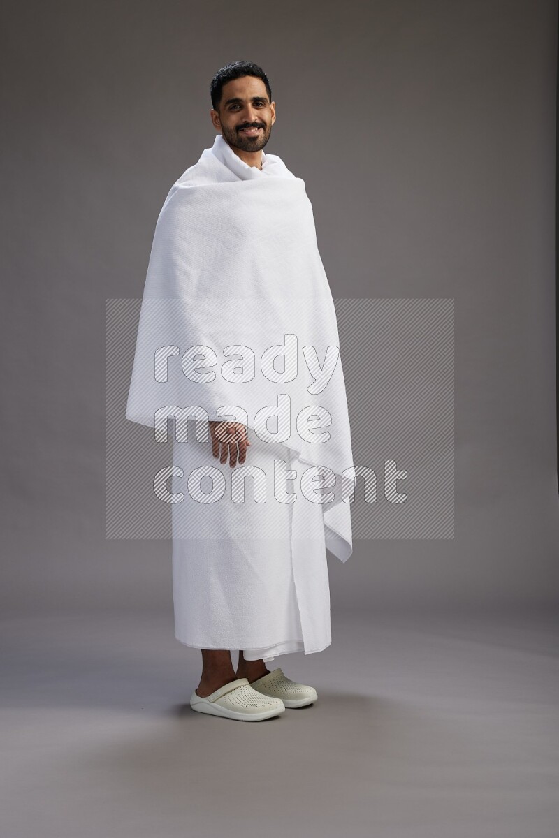 A man wearing Ehram Standing Interacting with the camera on gray background
