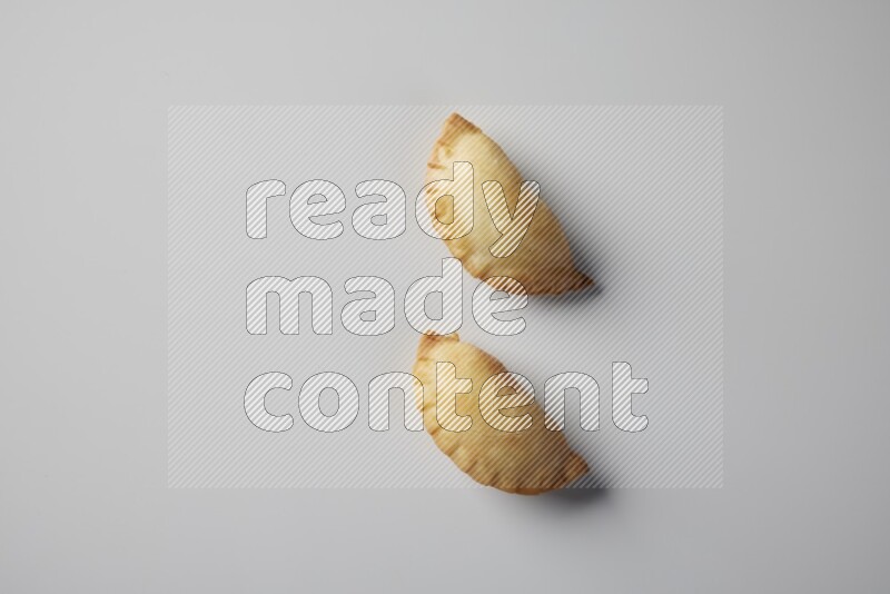 Two fried sambosa from a top angle on a white background