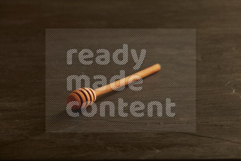 Wooden honey dipper on black slate background