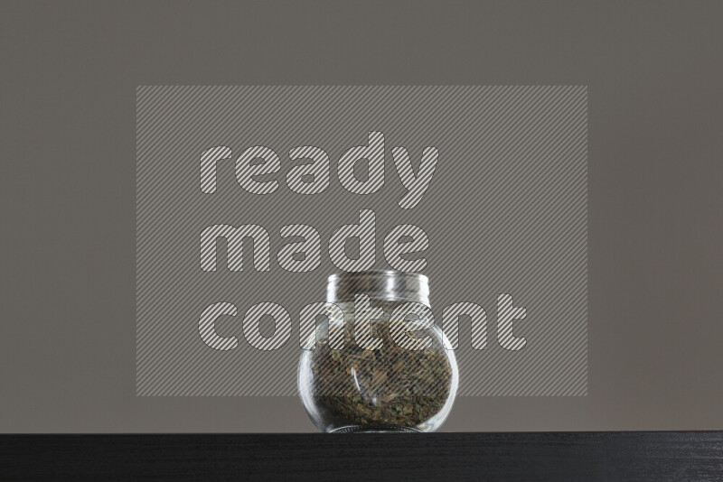 Dried basil in a glass jar on black background