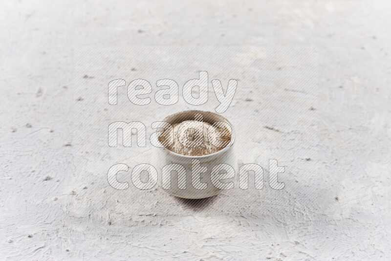 A beige pottery bowl full of onion powder on white background