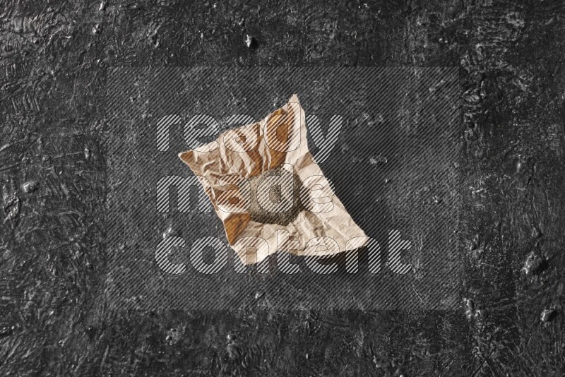 Black pepper powder on crumpled paper on a textured black flooring