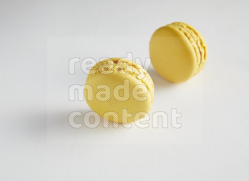 45º Shot of two Yellow Lemon macarons on white background