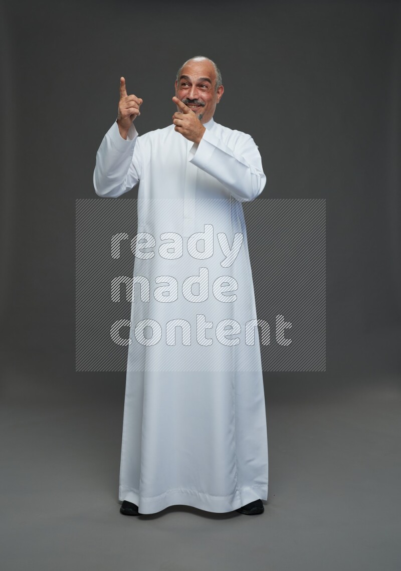 Saudi man without shomag Standing Interacting with the camera on gray background