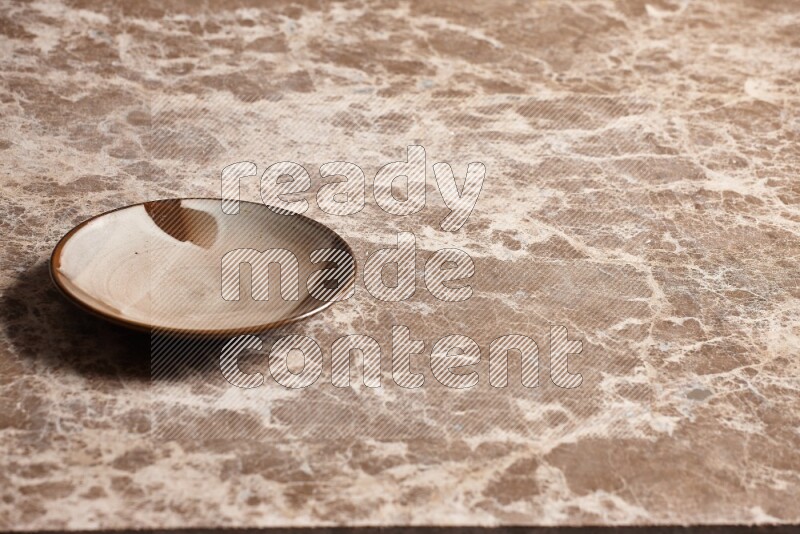 A multicolored pottery plate on beige marble background