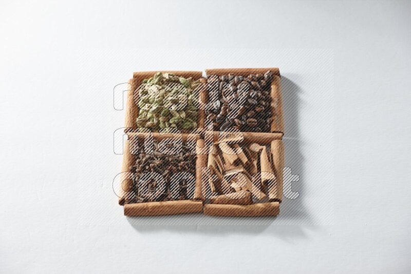 4 squares of cinnamon sticks full of coffee beans, cinnamon, cloves and cardamom on white flooring