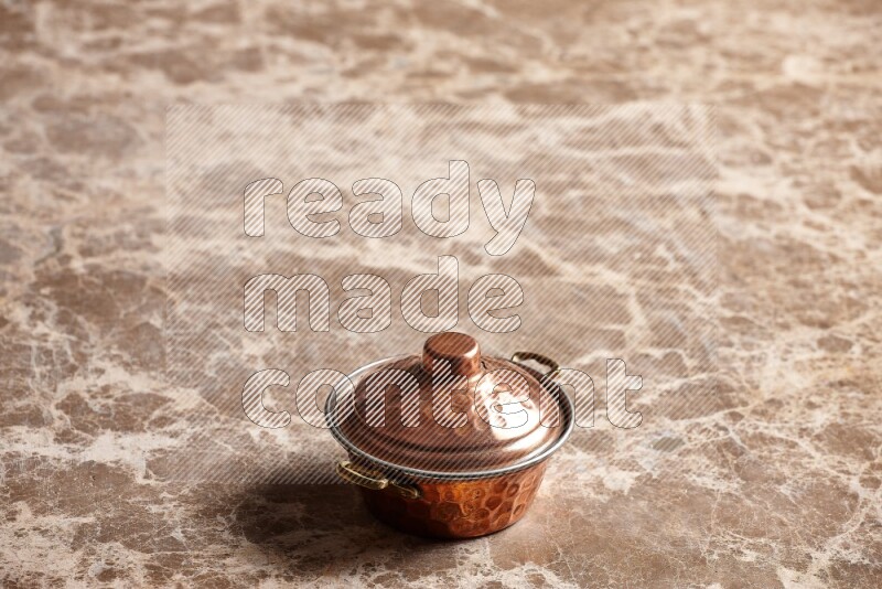 A small copper pot on beige marble background