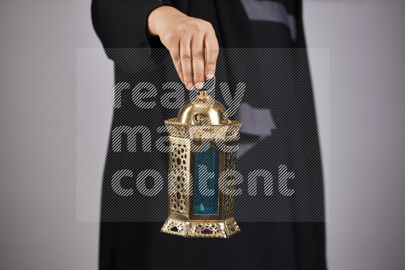 A woman in black abaya holding different ramadan lanterns in different positions