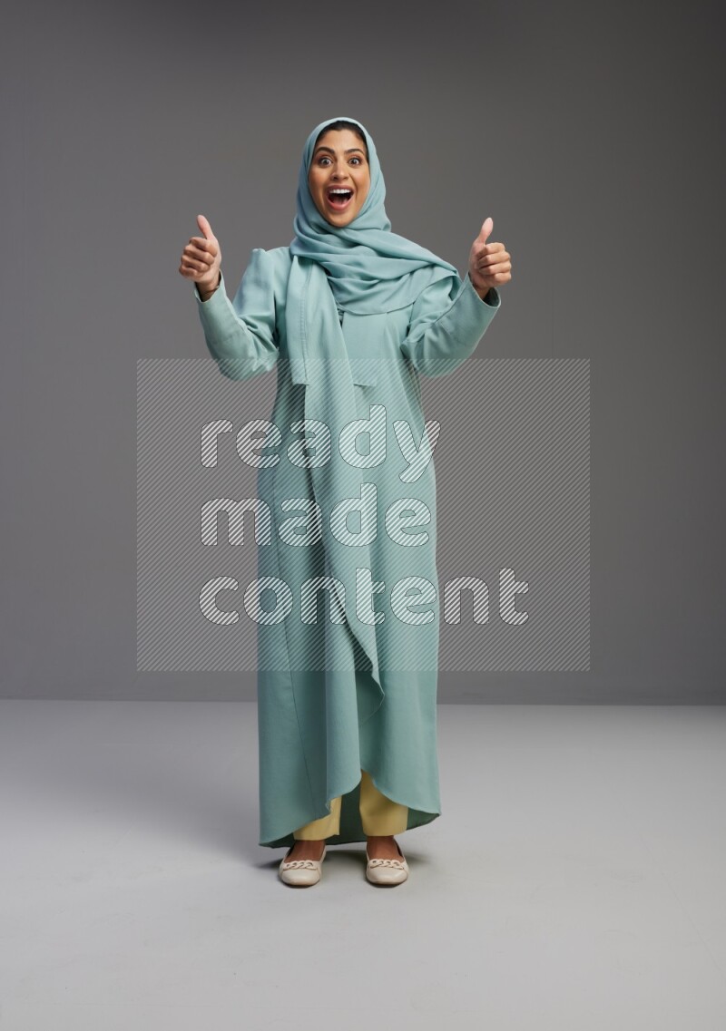 Saudi Woman wearing Abaya standing interacting with the camera on Gray background