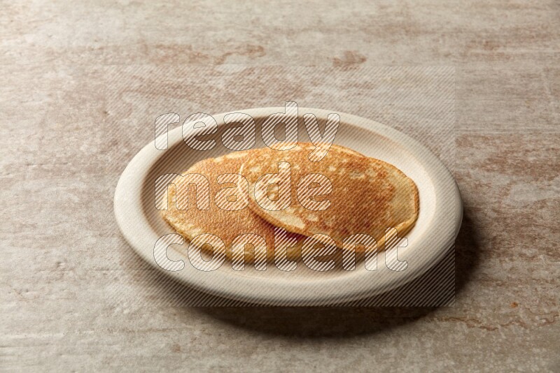Two stacked plain pancakes in a beige plate on beige background