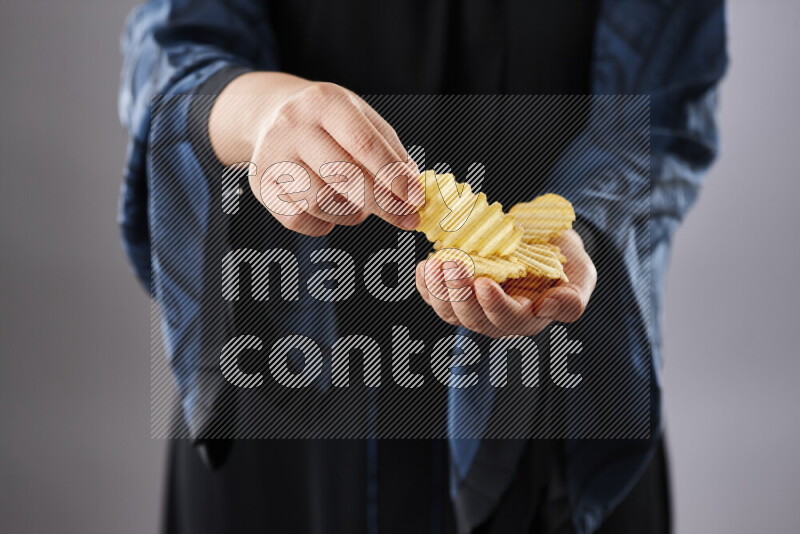 Woman in abaya holding different kinds of snacks in different positions
