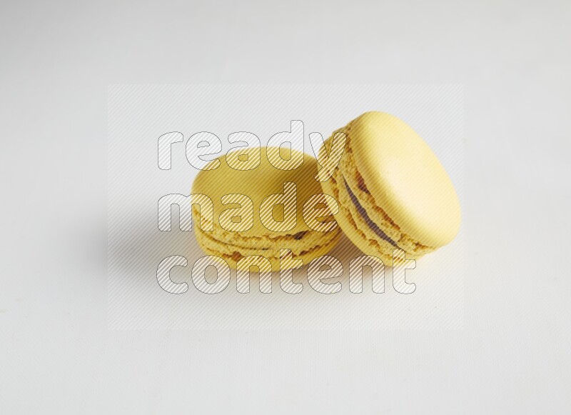 45º Shot of two Yellow Lemon macarons on white background