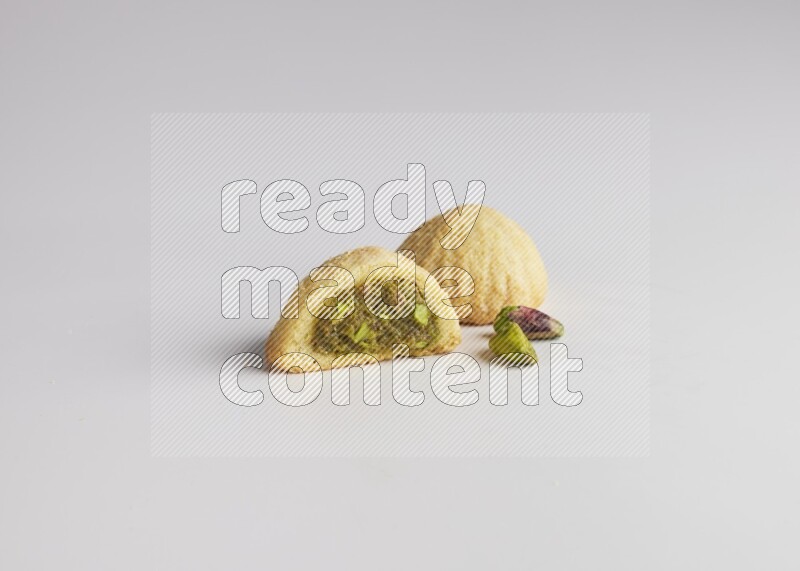 Two Pieces of Maamoul filled with pistachio paste  one of them is cut direct on white background