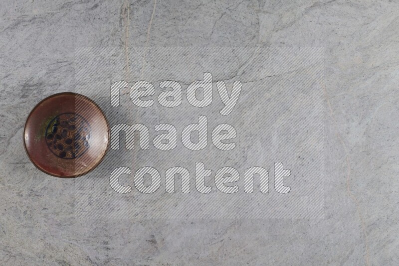 A decorative pottery plate on grey marble background
