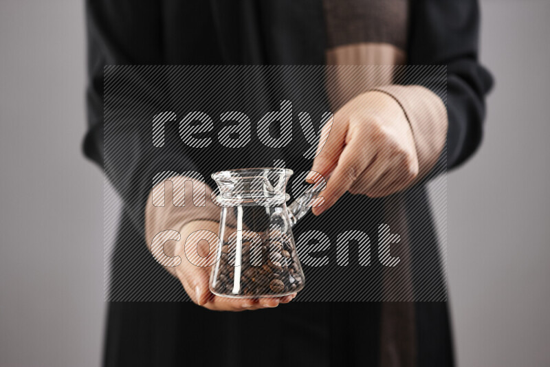 Woman in abaya holding different kinds of coffee beans in different positions