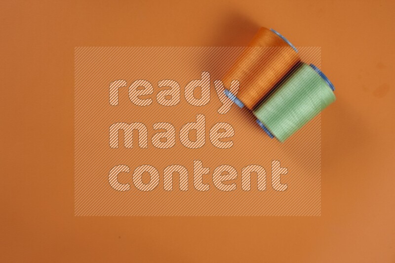 A green and orange collection of sewing and tailoring tools arranged on a orange background