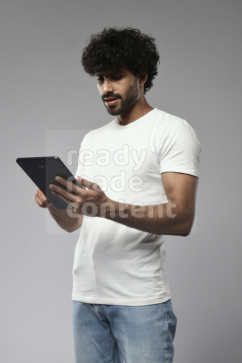 A man wearing casual standing and browsing on a tablet on white background