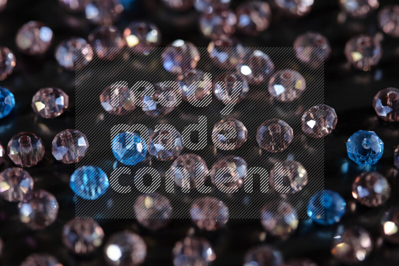 Rose and blue transparent crystal beads scattered on a black background