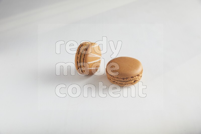 45º Shot of of two assorted Brown Irish Cream, and Brown Maple Taffy macarons  on white background