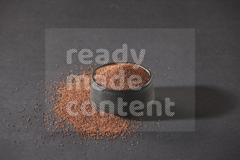 وعاء فخاري أسود ممتلئ ببذور حب الرشاد محاط بالبذور على أرضية سوداء