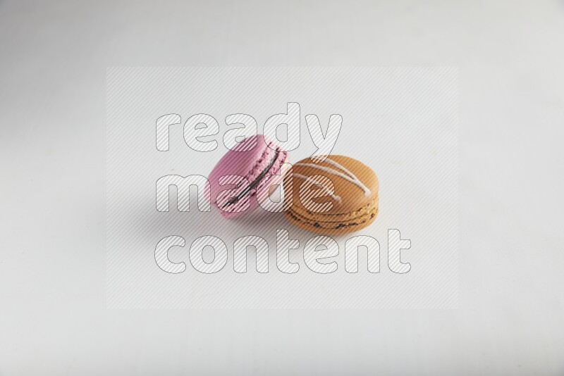 45º Shot of of two assorted Brown Irish Cream, and Purple Strawberry macarons on white background