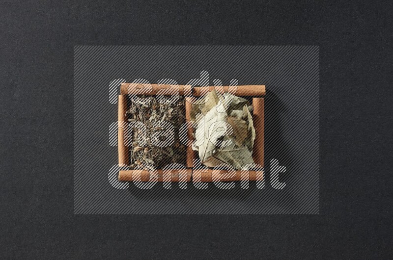 2 squares of cinnamon sticks full of bay laurel leaves and dried basil on black flooring