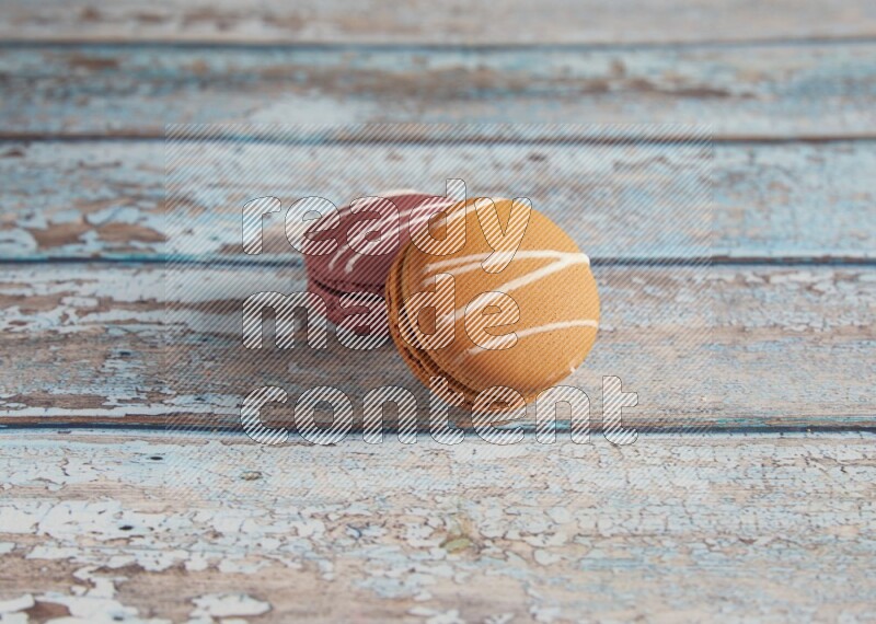 45º Shot of of two assorted Brown Irish Cream, and Red Poppy Flower macarons  on light blue background