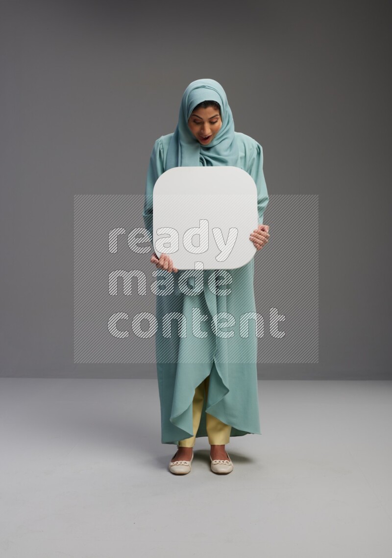 Saudi Woman wearing Abaya standing holding social media sign on Gray background