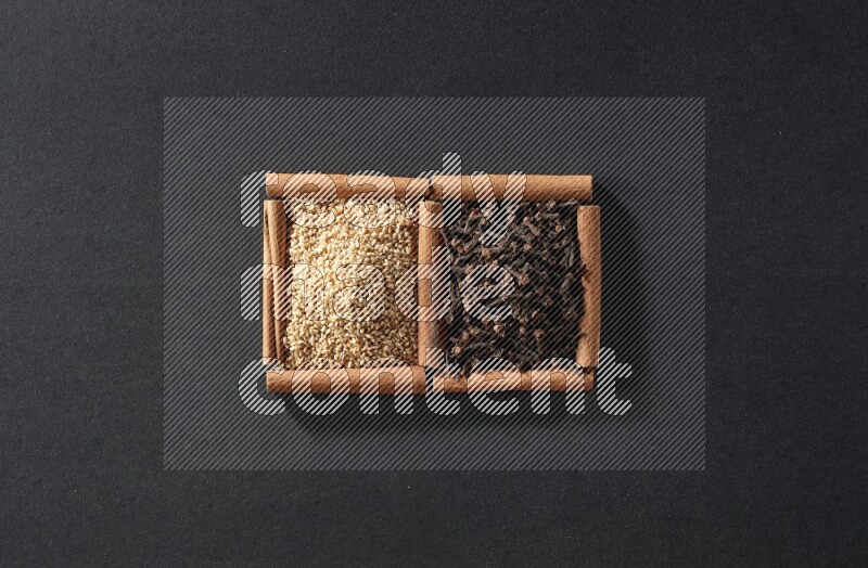 2 squares of cinnamon sticks full of sesame and cloves on black flooring