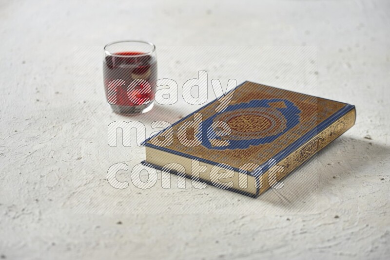 Quran with dates, prayer beads and different drinks all placed on textured white background