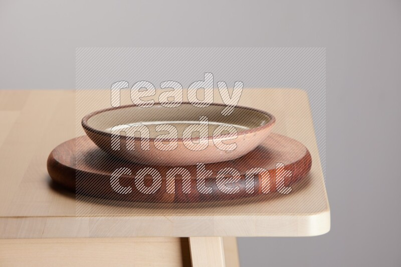multi-colored pottery Plate placed on a dark colored wooden tray on the edge of wooden table