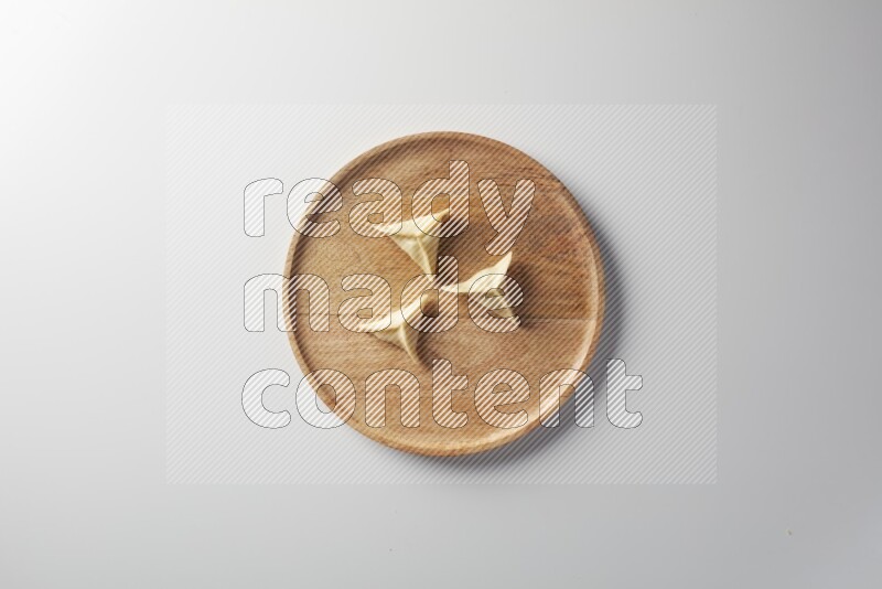 Three Sambosas on a wooden round plate on a white background