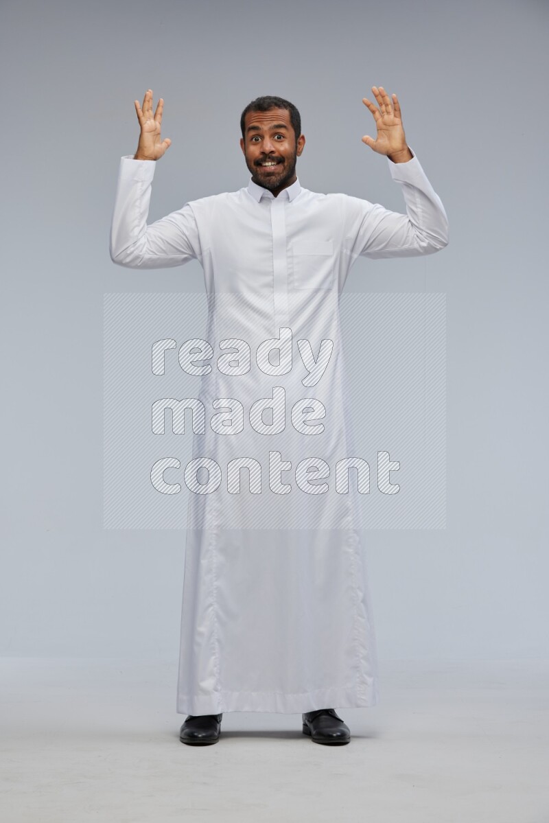 Saudi man Wearing Thob standing interacting with the camera on Gray background
