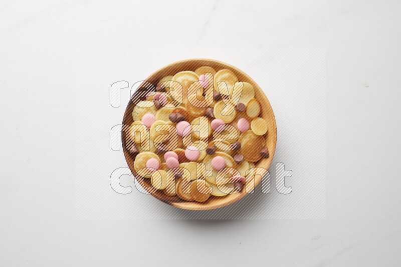 Top-view shot of mixed chocolate chips cereal pancakes in a round bowl on white background