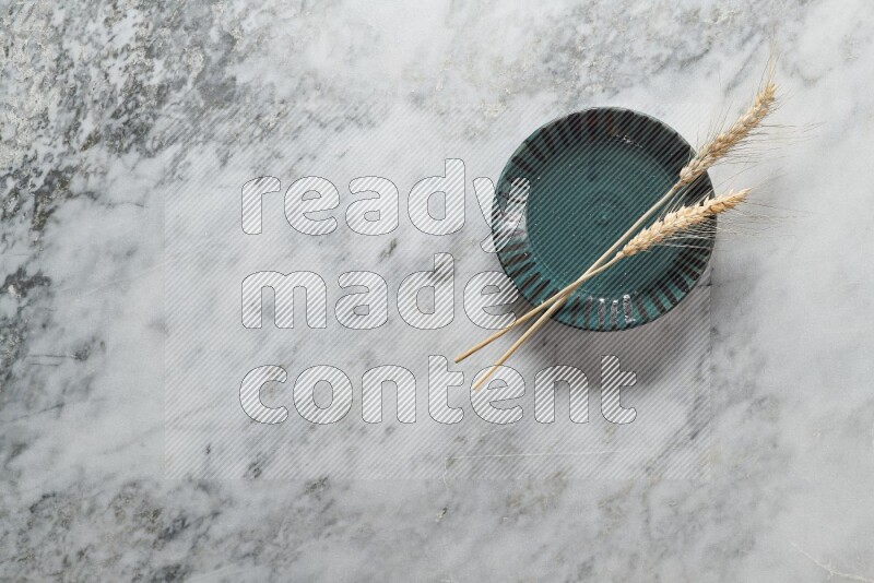 Wheat stalks on multicolored pottery plate on grey marble background