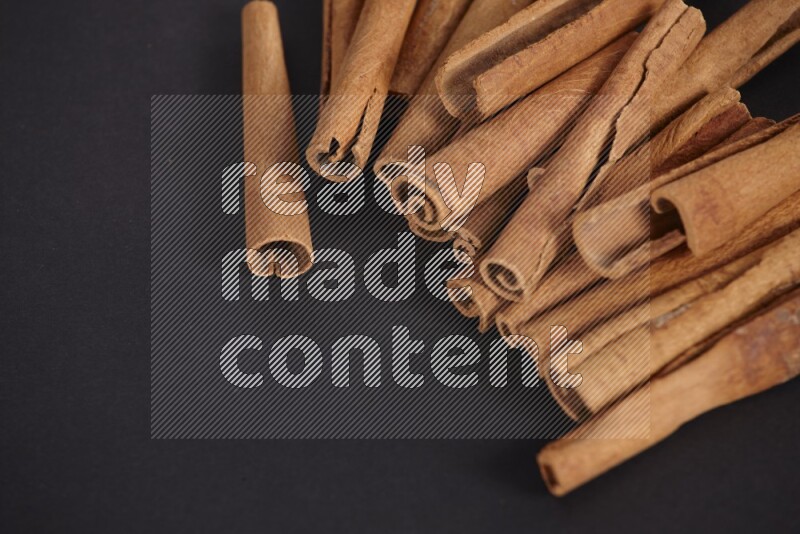 Cinnamon sticks stacked on black flooring