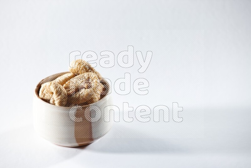 A beige ceramic bowl full of dried figs on a white background in different angles