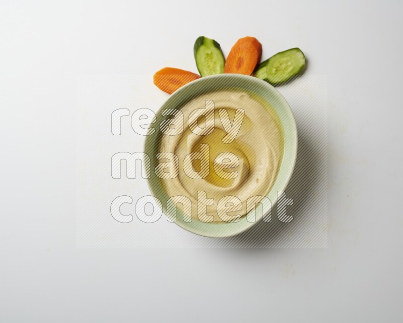 Hummus in a green plate garnished with olive oil on a white background