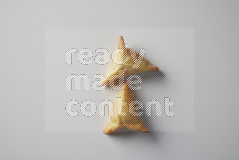 Two fried sambosa from a top angle on a white background