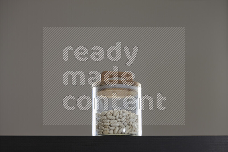 White beans in a glass jar on black background