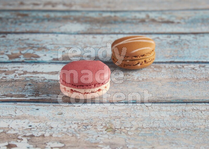 45º Shot of of two assorted Brown Irish Cream, and Pink Litchi Raspberry macarons on light blue background