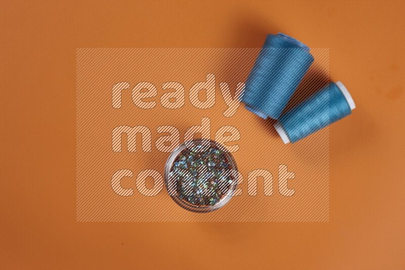 A blue collection of sewing and tailoring tools arranged on a orange background