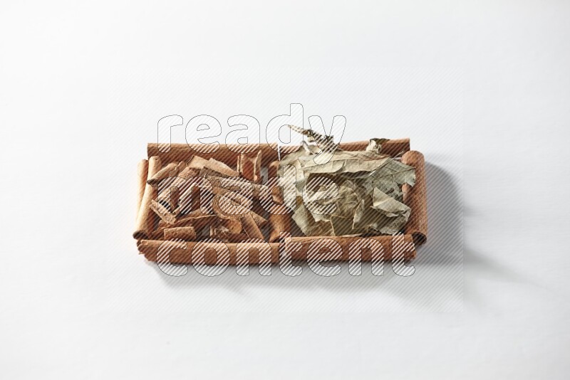2 squares of cinnamon sticks full of cinnamon and bay laurel leaves on white flooring